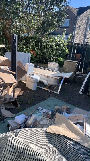A patio piled with an old bathroom suite, cardboard and household waste