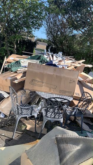 A patio table and chairs buried under cardboard and packaging waste